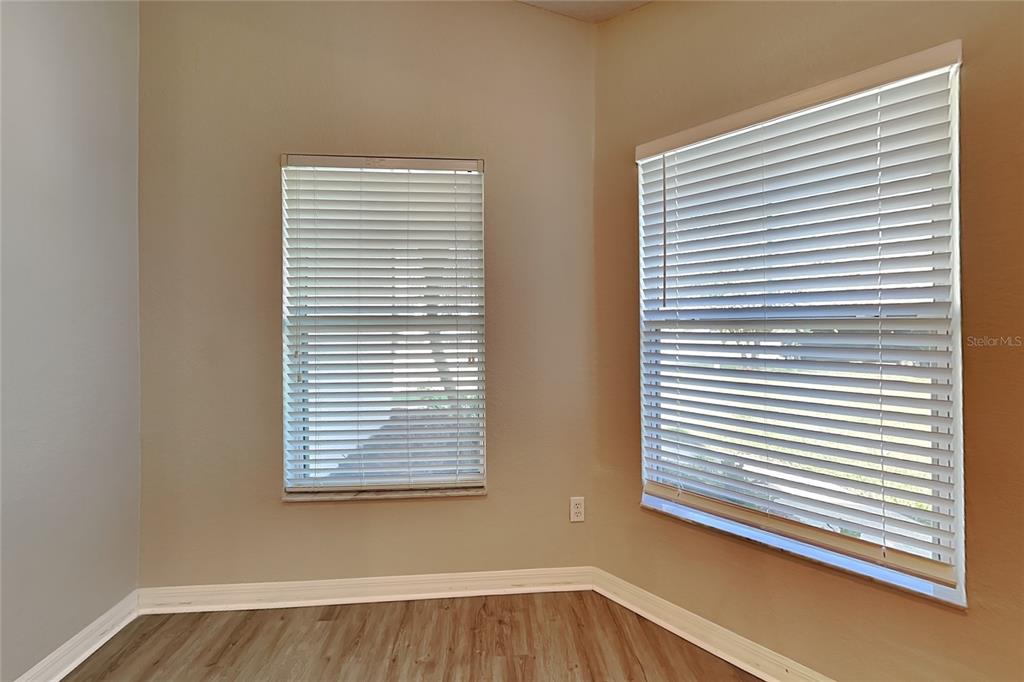 An empty room features light-colored walls, wood-look flooring, and two windows with white blinds — 3111 BUCKEYE POINTE DRIVE, WINTER HAVEN, FL