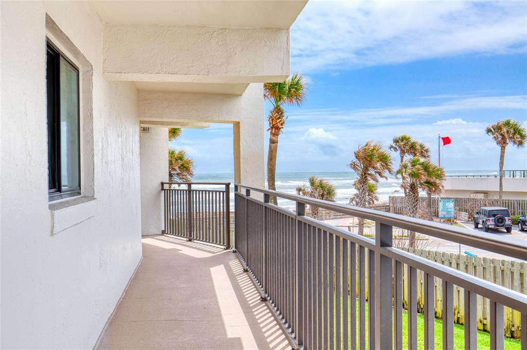 A balcony with metal railings overlooks the ocean and a parking area with palm trees — 1275 OCEAN SHORE BOULEVARD UNIT 2030, ORMOND BEACH, FL