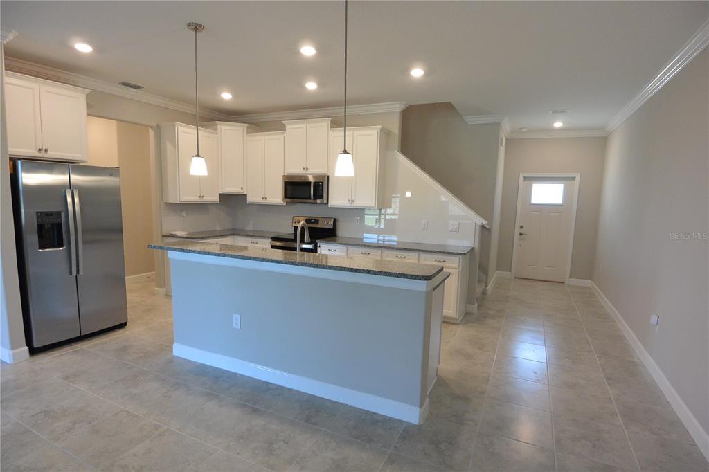 A kitchen features white cabinets, granite countertops, stainless steel appliances, and a breakfast bar — 2277 CERULEAN SKY DRIVE, LUTZ, FL