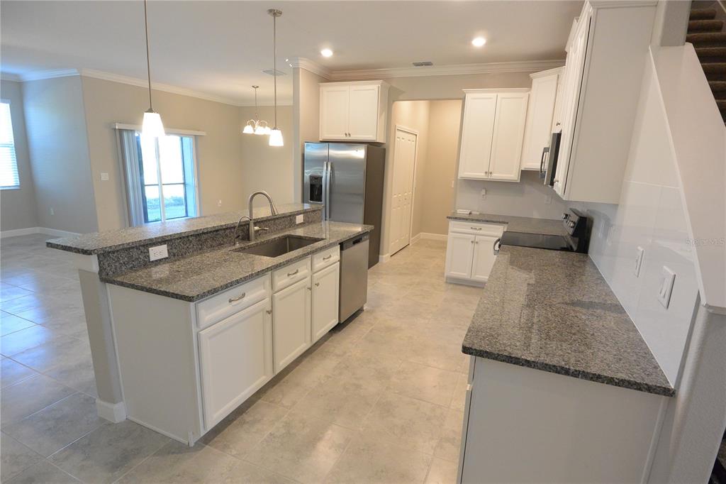 A kitchen features white cabinets, granite countertops, stainless steel appliances, and tile flooring — 2277 CERULEAN SKY DRIVE, LUTZ, FL
