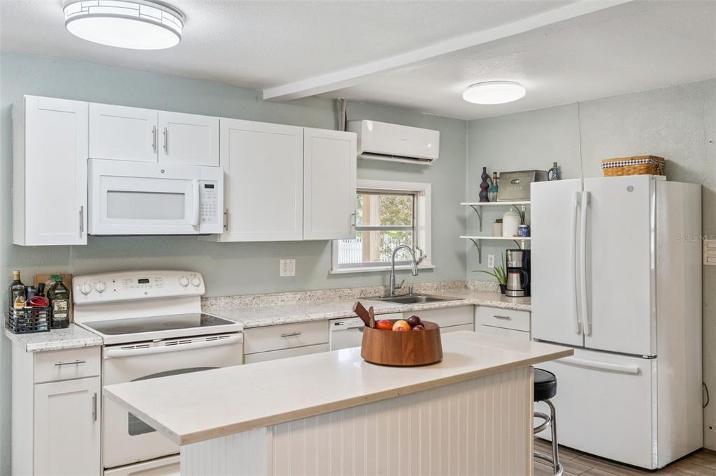 A kitchen features white cabinetry, white appliances, a center island, and light-colored countertops — 809 GRANDVIEW AVENUE, ALTAMONTE SPRINGS, FL