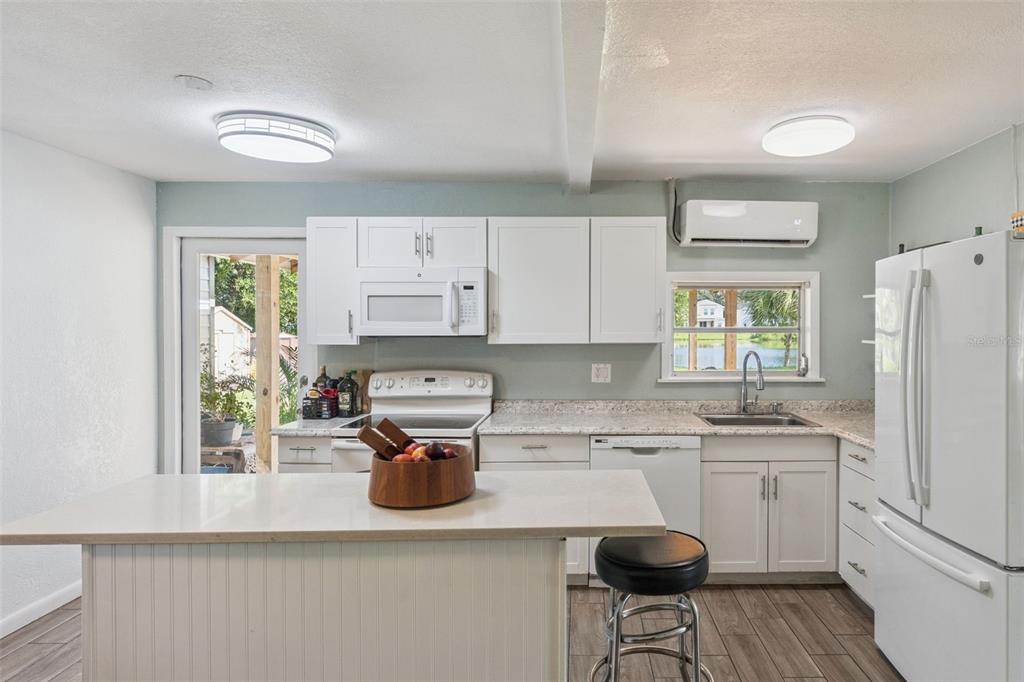 A kitchen with white cabinets, a central island, stainless steel appliances, and a view of water — 809 GRANDVIEW AVENUE, ALTAMONTE SPRINGS, FL
