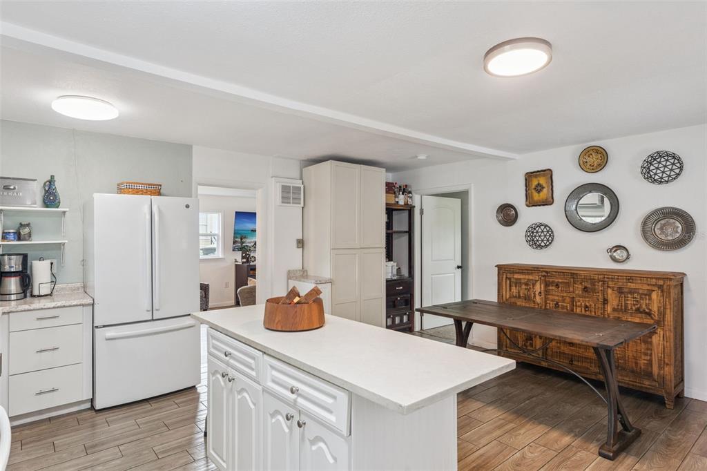 A kitchen features white cabinetry, a central island, a wooden dining table, and tile flooring — 809 GRANDVIEW AVENUE, ALTAMONTE SPRINGS, FL