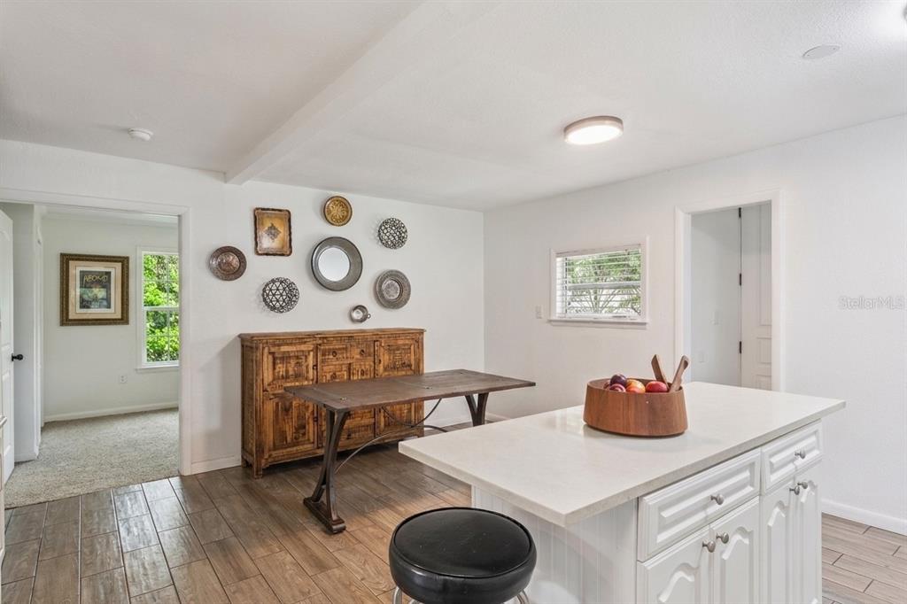 A dining area features a wooden sideboard, a table, and a kitchen island with seating — 809 GRANDVIEW AVENUE, ALTAMONTE SPRINGS, FL