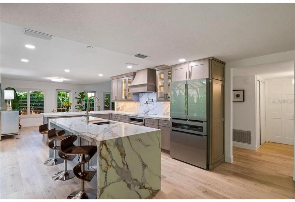 A modern kitchen features marble countertops, a waterfall island, and gray cabinetry — 128 WOODMILL ROAD, LONGWOOD, FL