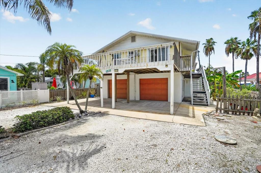 An elevated house with a gravel driveway, two garage doors, and a second-story balcony — 524 SPRING AVENUE, ANNA MARIA, FL