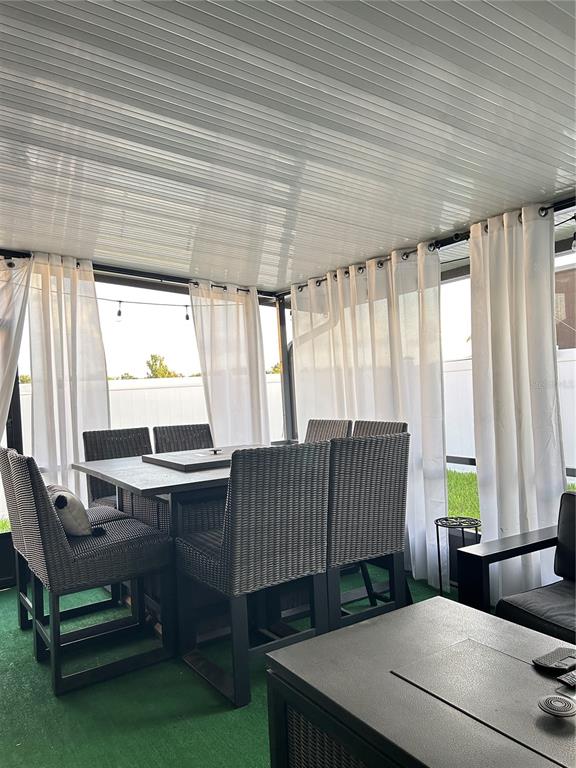 A covered outdoor patio features a dining set, wicker chairs, and white curtains — 12226 FAIRLAWN DRIVE, RIVERVIEW, FL