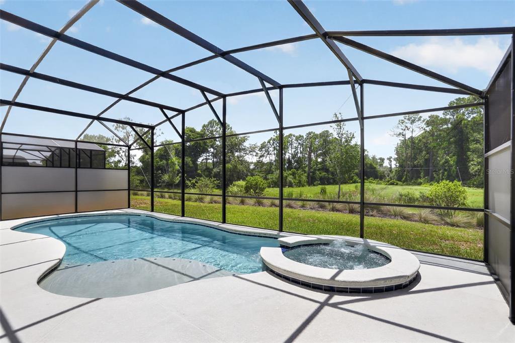 A two-story house with a screened-in pool and patio area in a grassy backyard — 1242 BUTTERFLY ORCHID ROAD, DAVENPORT, FL