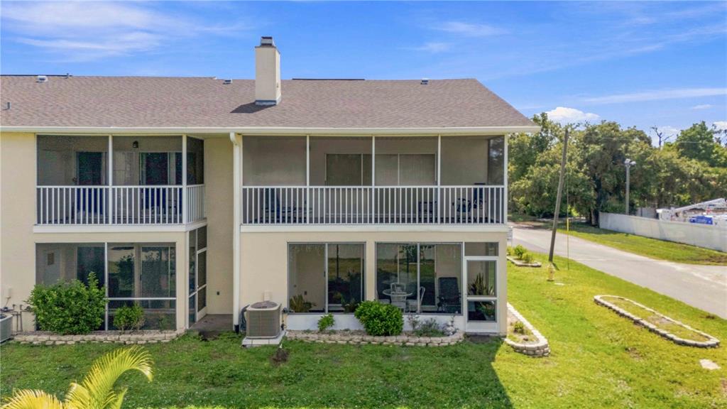 A two-story building features screened-in porches on both levels and a central chimney — 22278 VICK STREET UNIT A100, PORT CHARLOTTE, FL