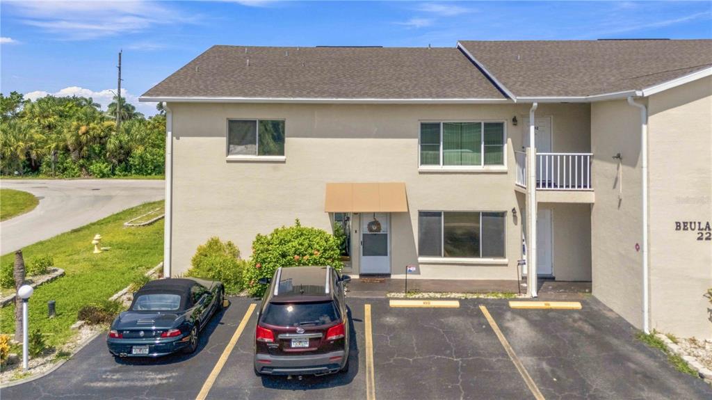 An exterior view of a two-story apartment building with two parked cars in front — 22278 VICK STREET UNIT A100, PORT CHARLOTTE, FL