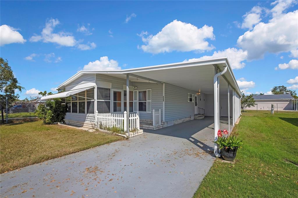 A single-story manufactured home features light gray siding, a covered carport, and a small porch — 4809 EMPRESS LANE, HOLIDAY, FL