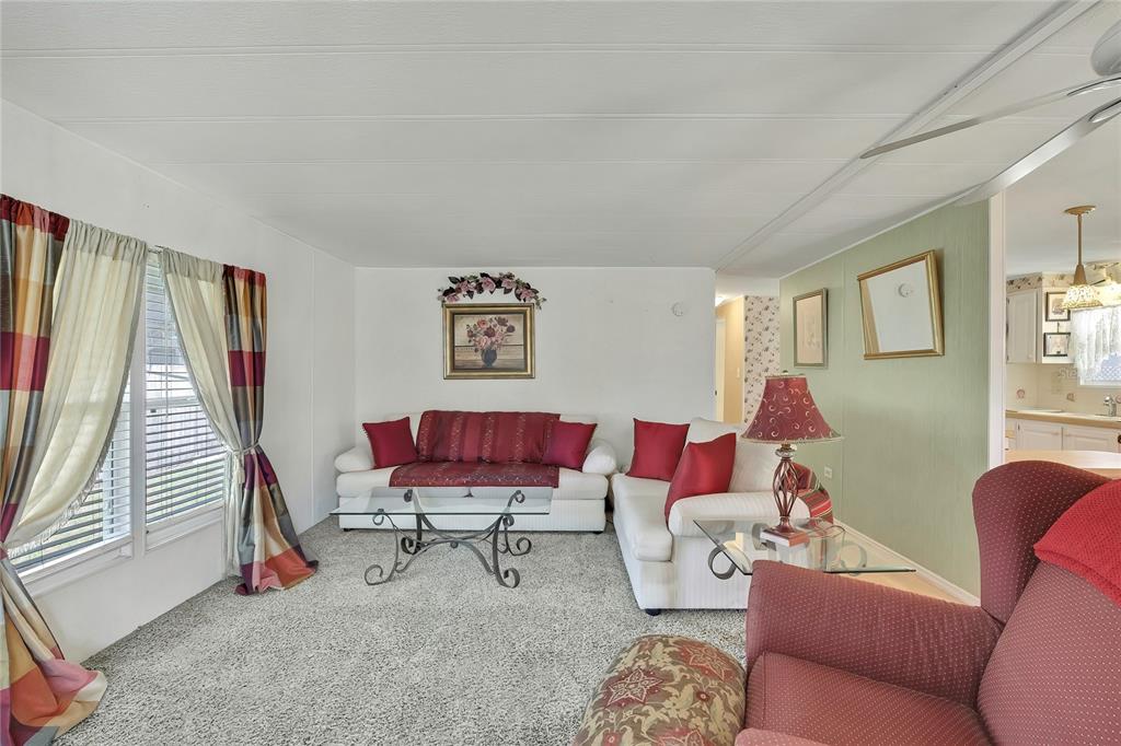 A living room features white sofas, a glass coffee table, and a red armchair — 4809 EMPRESS LANE, HOLIDAY, FL