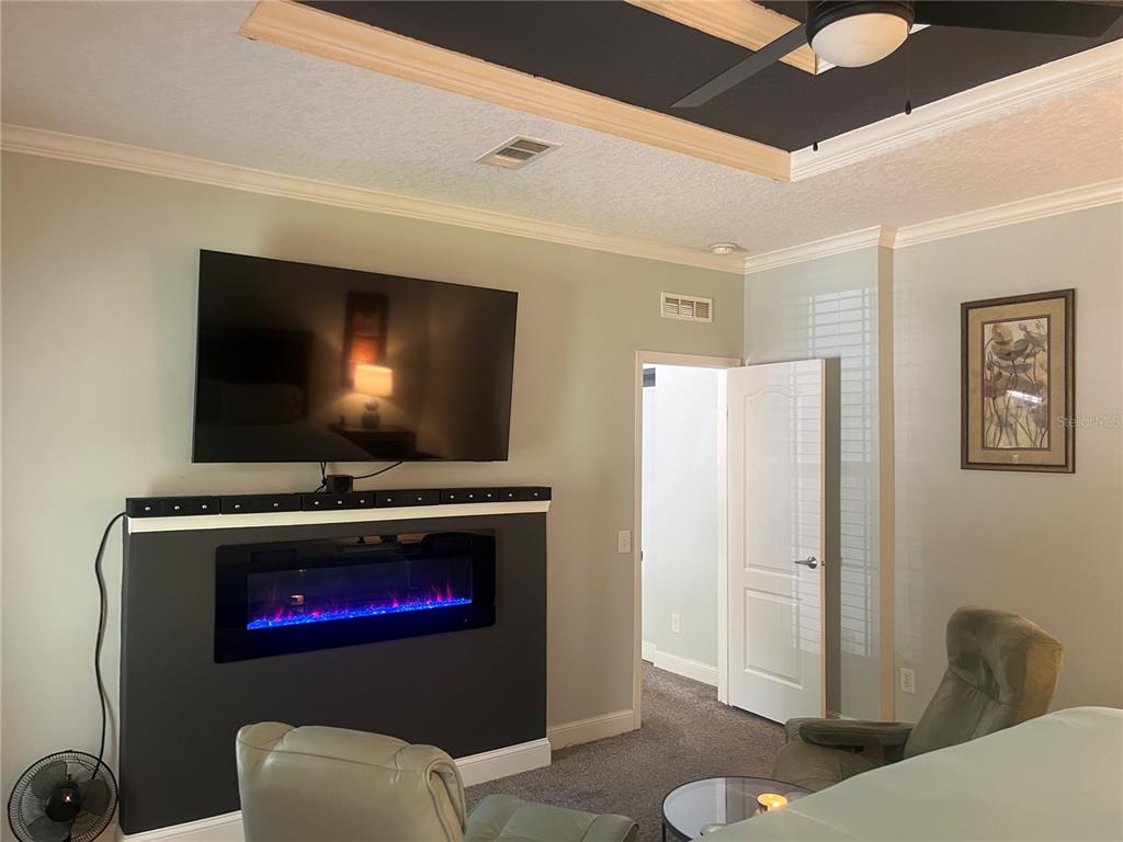 A living room features a wall-mounted television above a modern electric fireplace with blue flames — 4050 SW 178TH TERRACE, DUNNELLON, FL