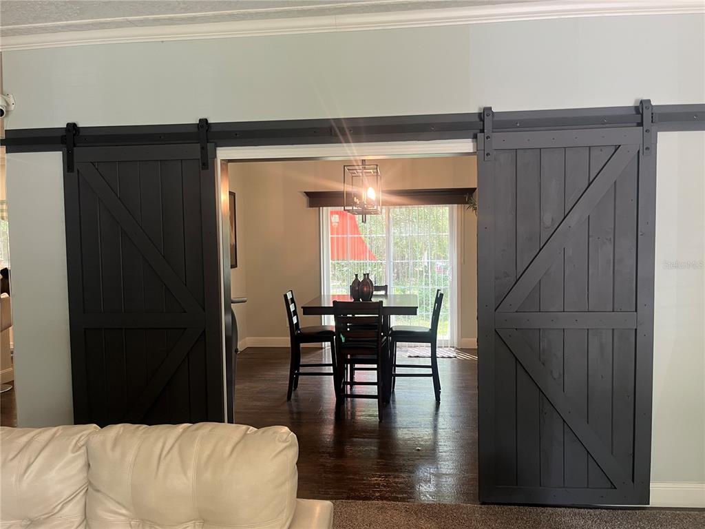 A dining room is visible through two black sliding barn doors in a living area — 4050 SW 178TH TERRACE, DUNNELLON, FL