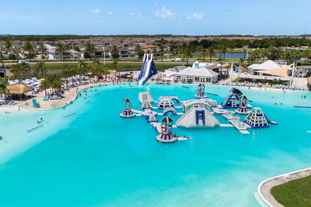 An aerial view of a large swimming lagoon featuring an inflatable obstacle course and slide — 31575 BARREL WAVE WAY, WESLEY CHAPEL, FL