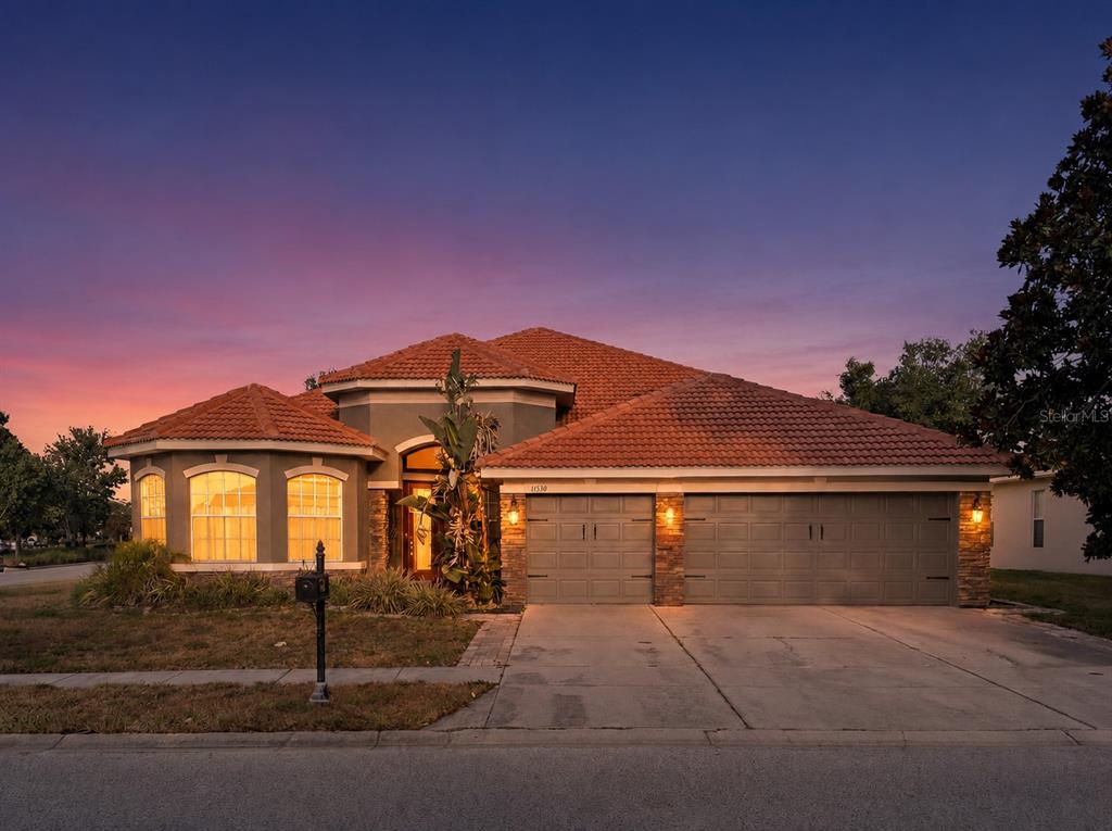 A single-story house with a terracotta tile roof, beige stucco walls, and a two-car garage — 11530 OYSTER BAY CIRCLE, NEW PORT RICHEY, FL