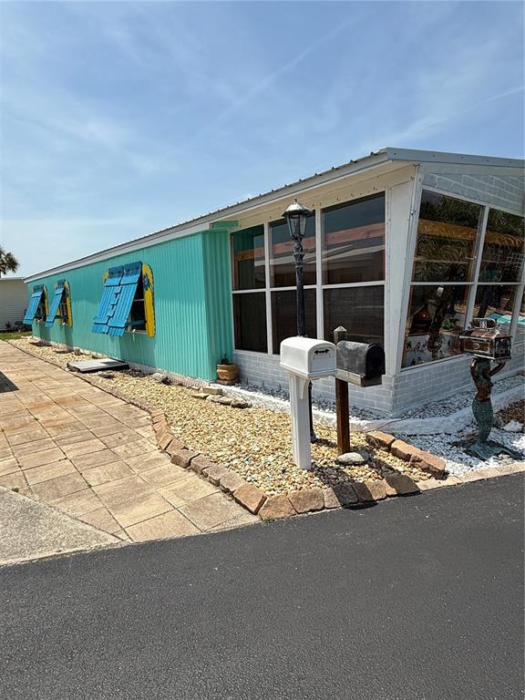 A turquoise mobile home features blue shutters, a screened-in porch, and a decorative mermaid statue — 89 MERRIMAC DRIVE, FLAGLER BEACH, FL