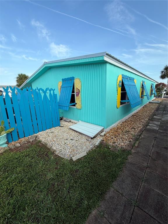 A turquoise mobile home features blue shutters shaped like flip-flops and a matching blue fence — 89 MERRIMAC DRIVE, FLAGLER BEACH, FL