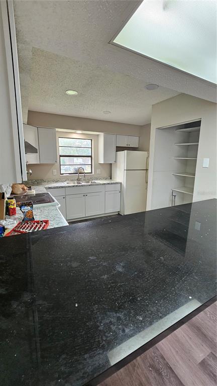 A kitchen with white cabinets, stainless steel appliances, and granite countertops opens to a living area — 3626 WILLOW OAK ROAD, MULBERRY, FL