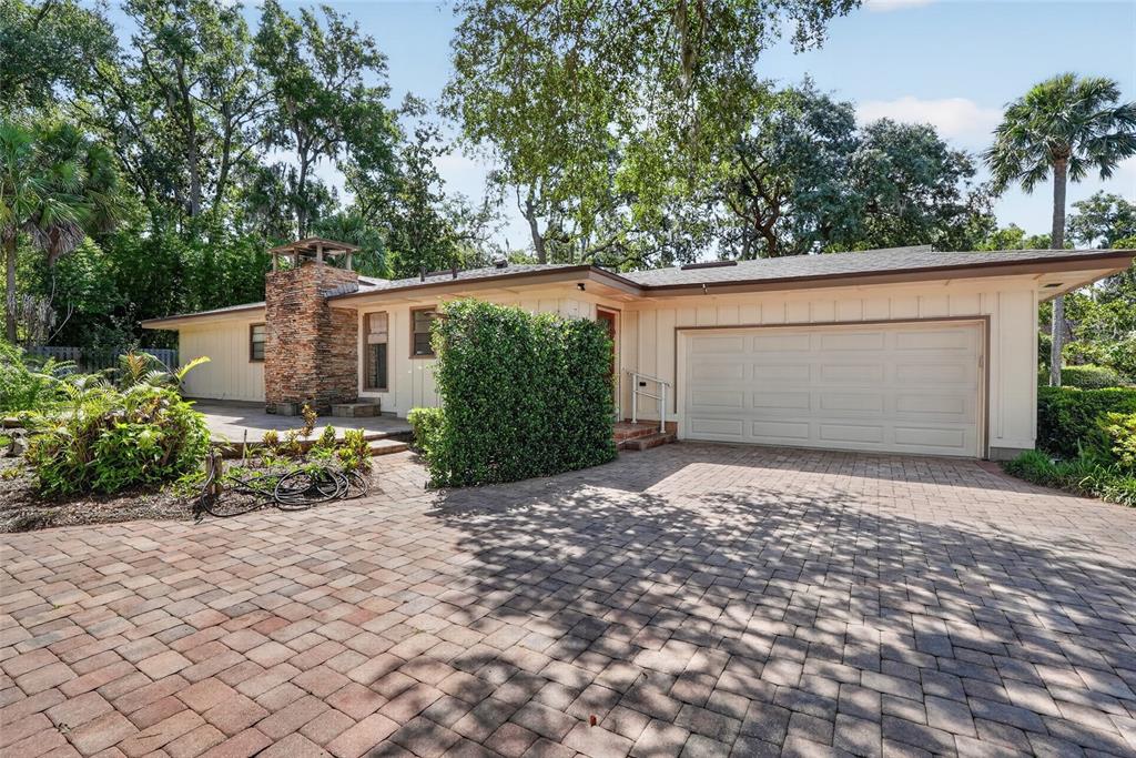 A single-story house with a stone chimney, a paved driveway, and a two-car garage — 2053 WOODY DRIVE, WINDERMERE, FL