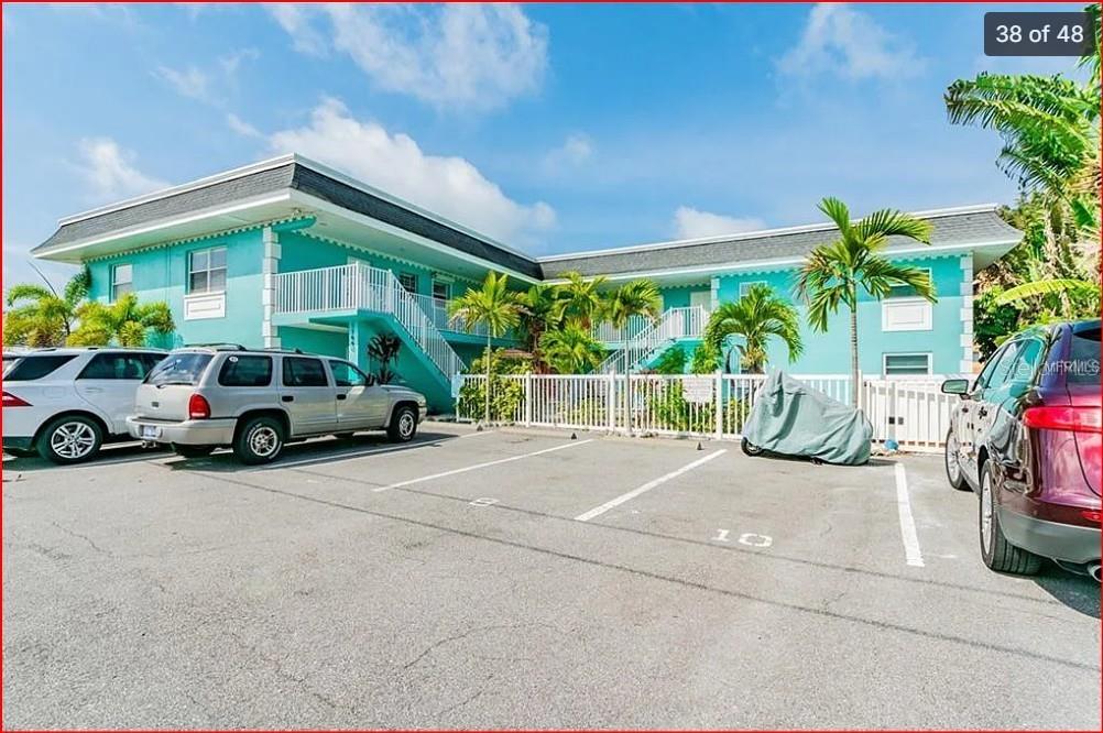 An aerial view shows a coastal residential area with apartment buildings, a canal, and beach — 11440 1ST STREET E UNIT 6, TREASURE ISLAND, FL
