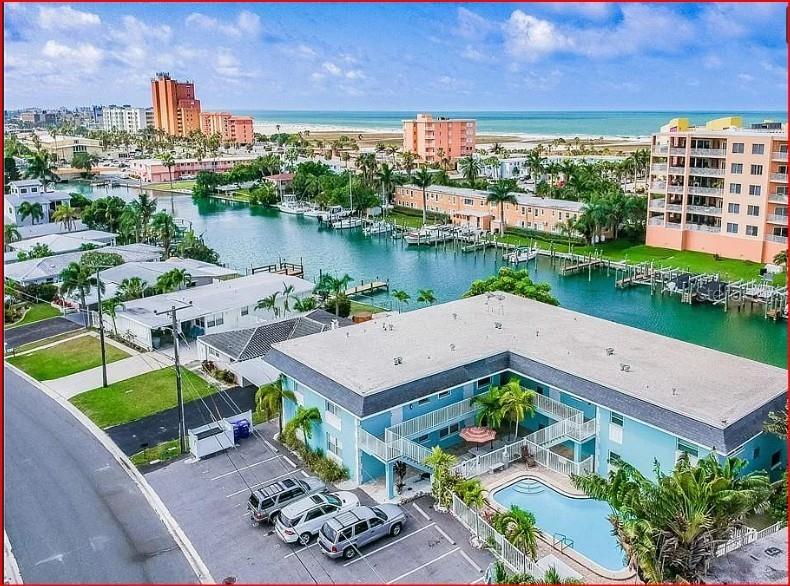 An aerial view of a waterfront residential neighborhood featuring a multi-unit building with boat docks — 11440 1ST STREET E UNIT 6, TREASURE ISLAND, FL