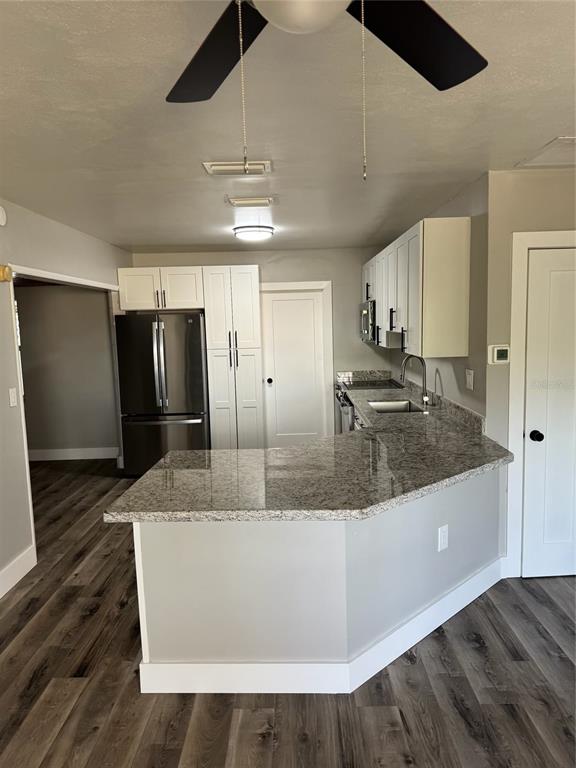 A kitchen features white cabinets, granite countertops, stainless steel appliances, and wood-look flooring — 104 POCONO TRAIL W UNIT b, NOKOMIS, FL