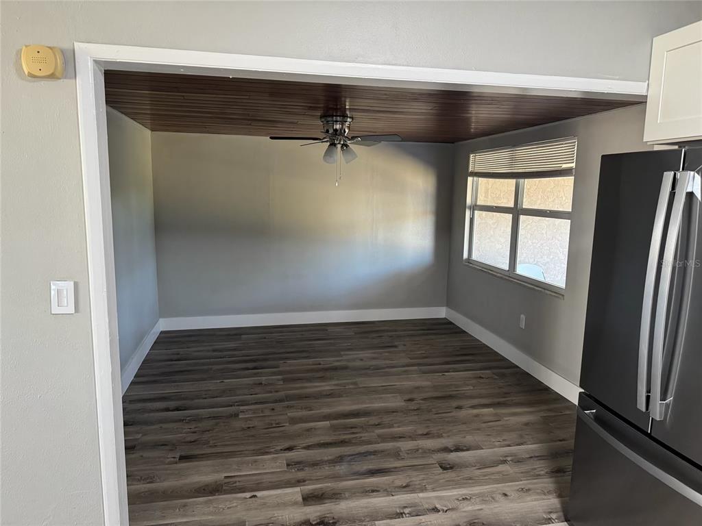 An empty dining area features wood-plank ceiling panels, a ceiling fan, and gray wood-look flooring — 104 POCONO TRAIL W UNIT b, NOKOMIS, FL