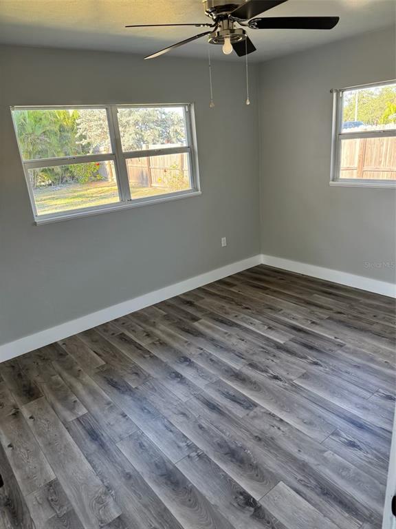 A bedroom with gray walls, wood-look flooring, a ceiling fan, and two windows — 104 POCONO TRAIL W UNIT b, NOKOMIS, FL