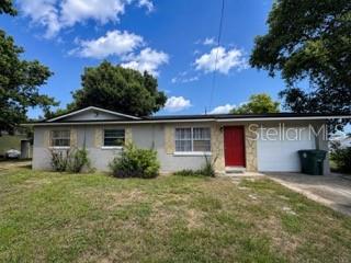 A single-story house with a red front door, a garage, and a grassy front yard — 729 LOTUS LANE, DAYTONA BEACH, FL