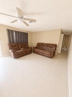 A living room with light tile floors, a ceiling fan, and two brown leather sofas — 729 LOTUS LANE, DAYTONA BEACH, FL