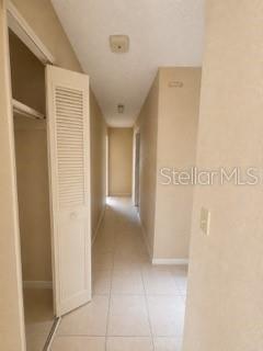 A narrow hallway with light-colored tile flooring and a white louvered closet door on the left — 729 LOTUS LANE, DAYTONA BEACH, FL