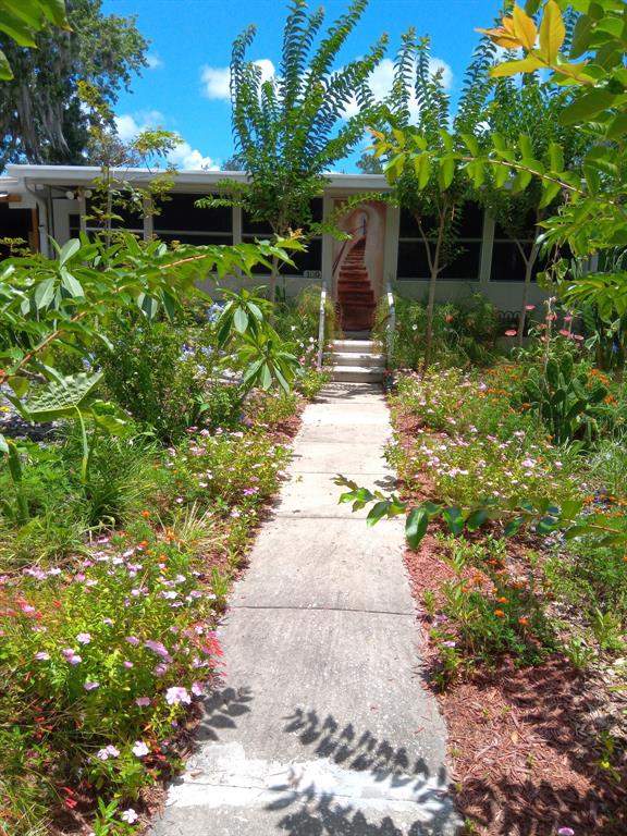 A concrete walkway leads to the front entrance of a house surrounded by lush landscaping — 109 FERN DRIVE, DEBARY, FL