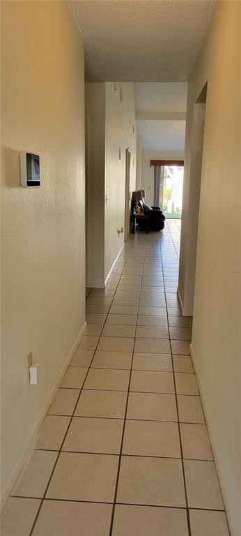 A tiled hallway leads from the foreground toward a living area with a dark sofa — 2218 ABBEY ROAD, WINTER HAVEN, FL