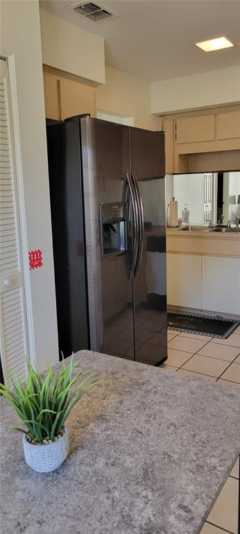 A kitchen features a dark refrigerator, light cabinetry, a tiled floor, and a gray countertop — 2218 ABBEY ROAD, WINTER HAVEN, FL