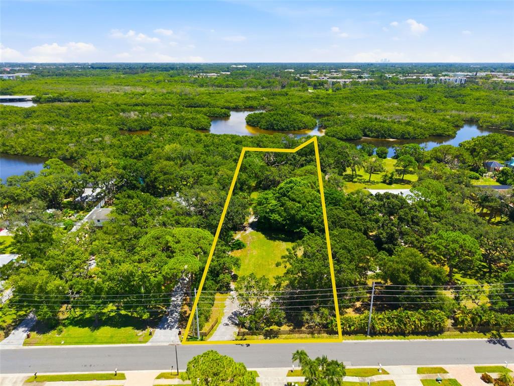 An aerial view shows a vacant, tree-lined lot outlined in yellow along a paved road — 6495 BURNING TREE DRIVE, SEMINOLE, FL