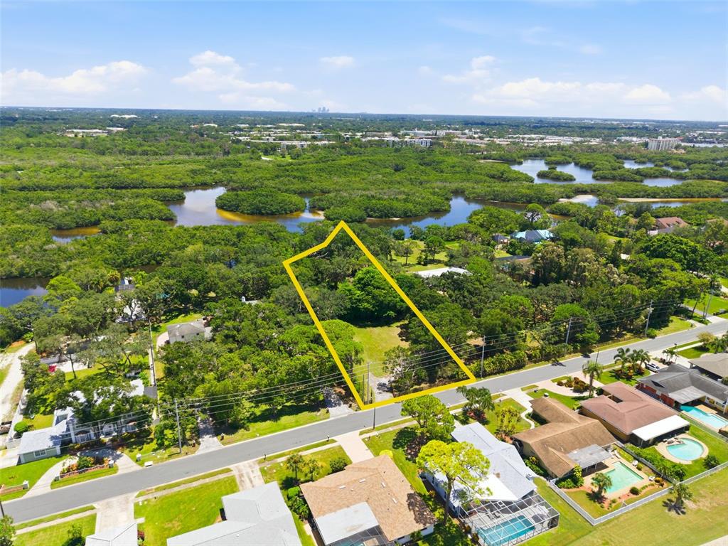 An aerial view shows a vacant, tree-lined residential lot outlined in yellow near a waterway — 6495 BURNING TREE DRIVE, SEMINOLE, FL