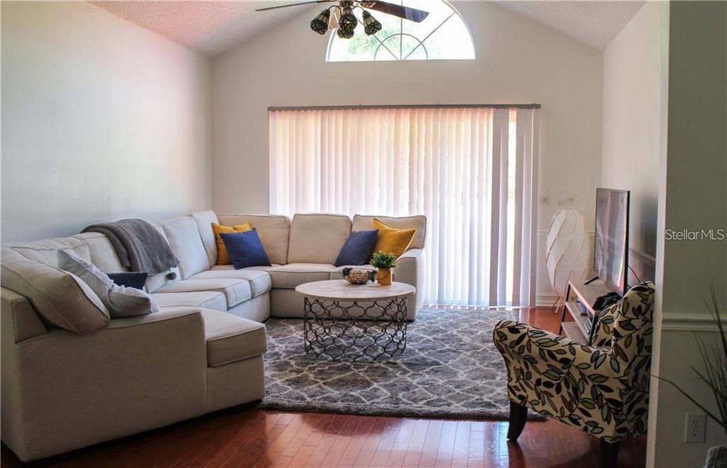 A living room features a large sectional sofa, a patterned area rug, and hardwood floors — 2630 STANTON HALL COURT, WINDERMERE, FL