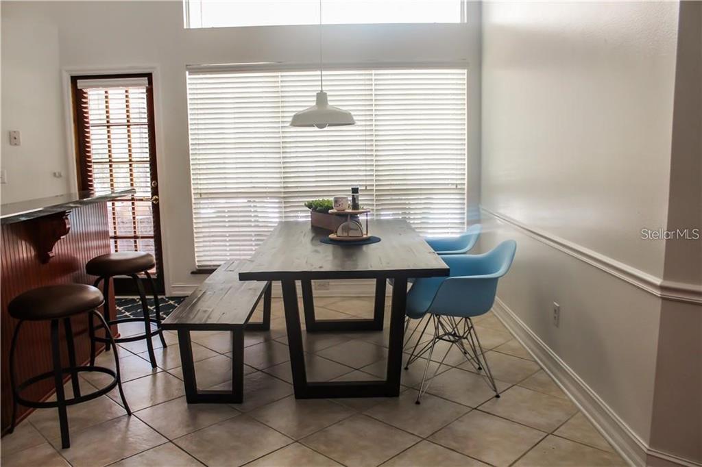 A dining area features a wooden table with a bench and two blue chairs — 2630 STANTON HALL COURT, WINDERMERE, FL