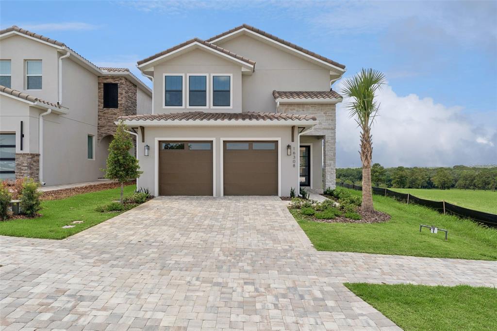 A two-story suburban house with a two-car garage, stone accents, and a paved driveway — 16308 VETTA DRIVE, MONTVERDE, FL