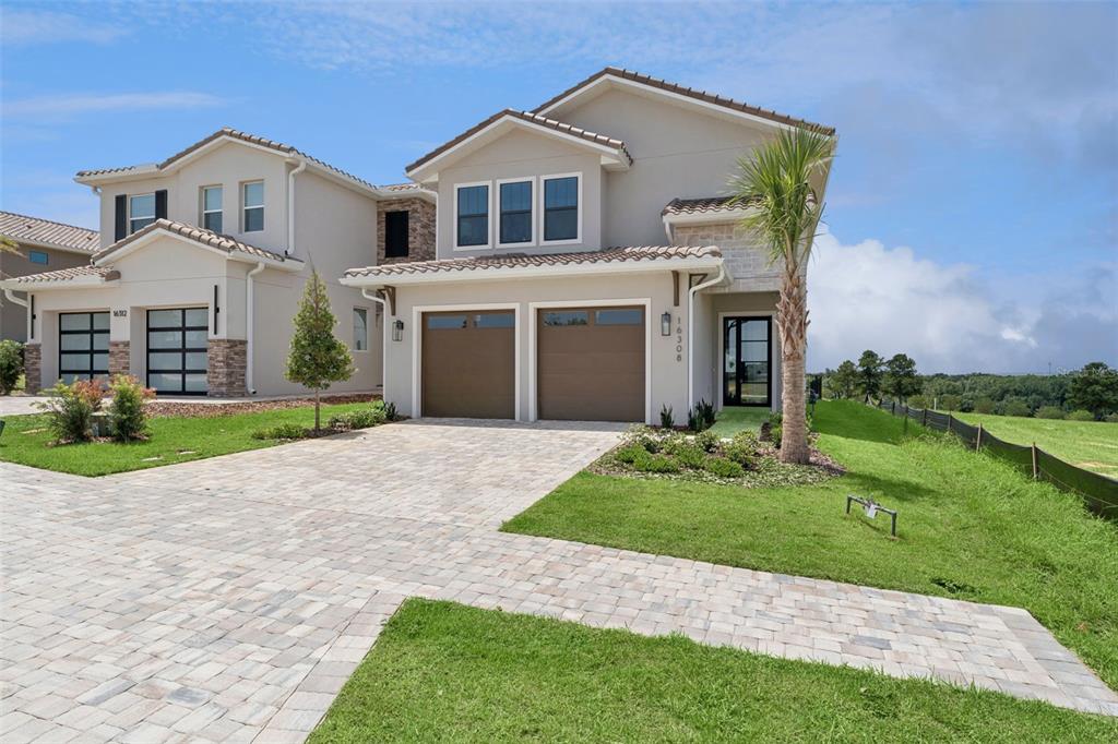 A two-story suburban house with a paver driveway, two-car garage, and a side yard — 16308 VETTA DRIVE, MONTVERDE, FL