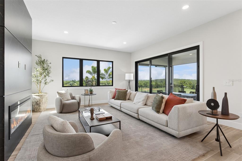 A modern living room features a fireplace, a large sectional sofa, and sliding glass doors — 16308 VETTA DRIVE, MONTVERDE, FL