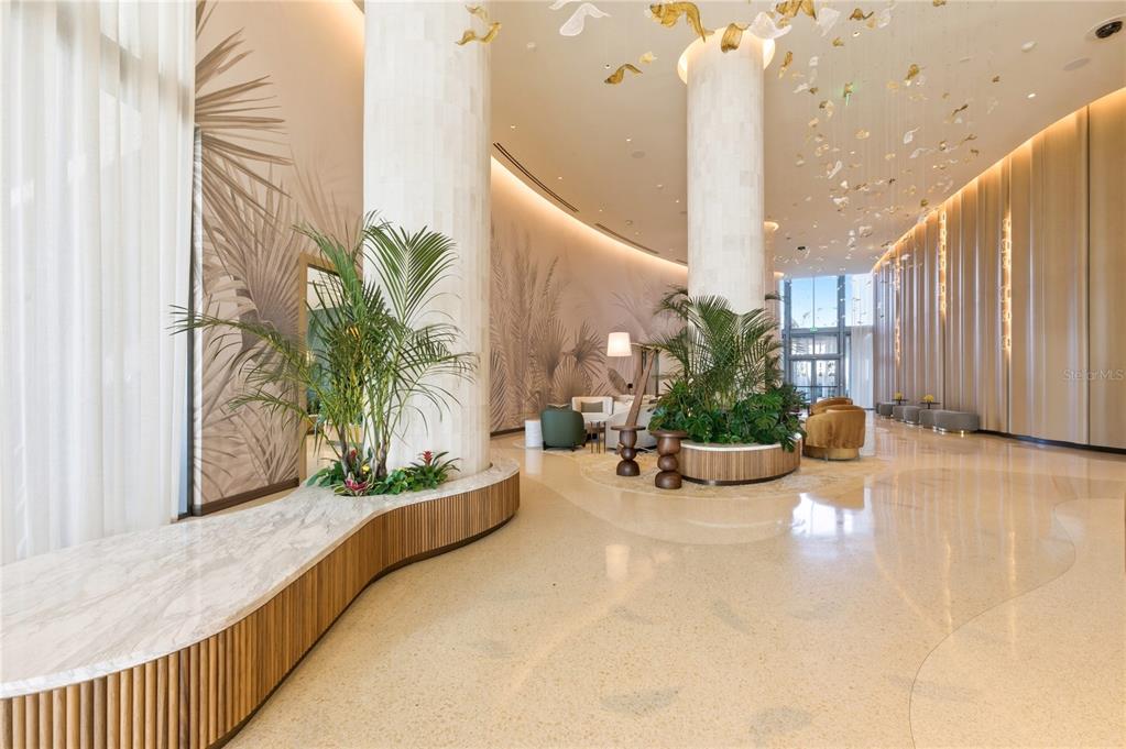 A spacious, modern hotel lobby features tall columns, marble floors, and large indoor potted plants — 5100 COCONUT ROAD UNIT 705, ESTERO, FL