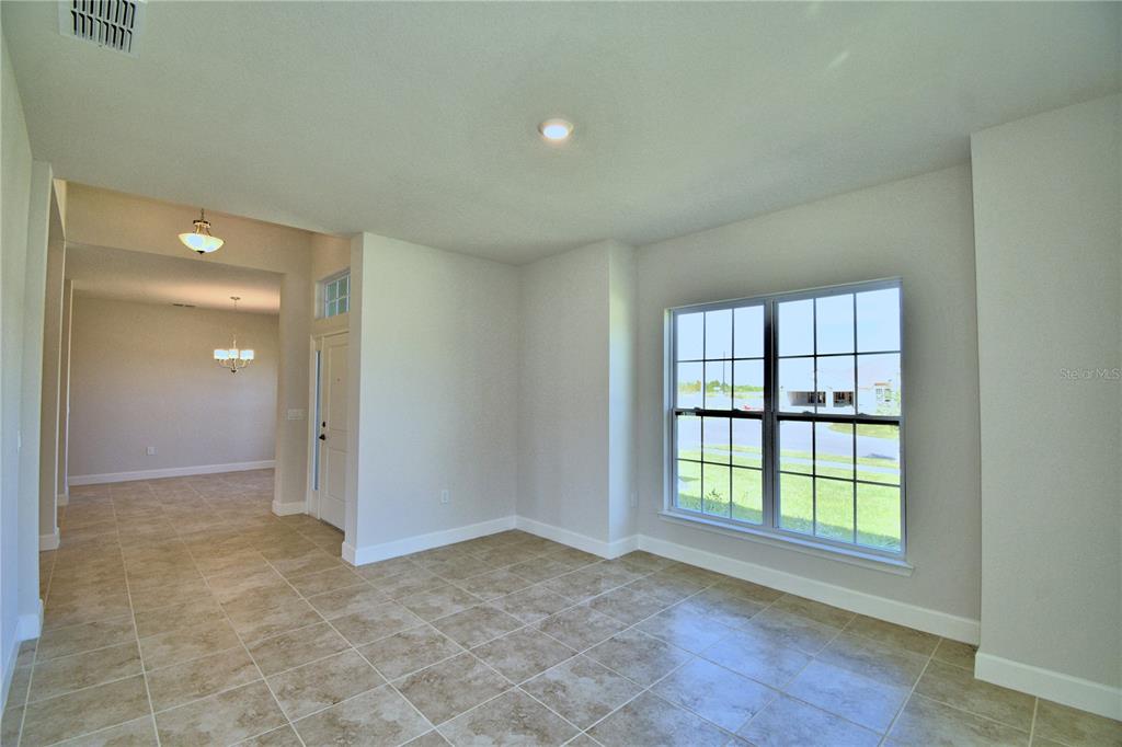 An empty room with tiled floors, a large window, and an adjacent entryway — 4615 CALAMINT LANE, AUBURNDALE, FL