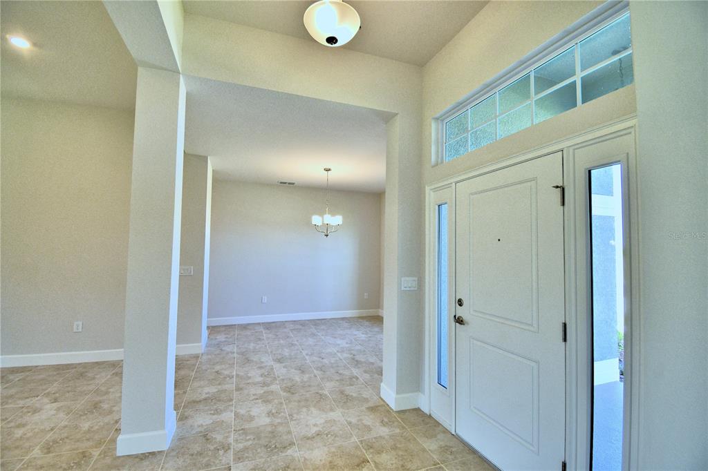 An entryway with tile flooring leads to a dining area featuring a chandelier — 4615 CALAMINT LANE, AUBURNDALE, FL