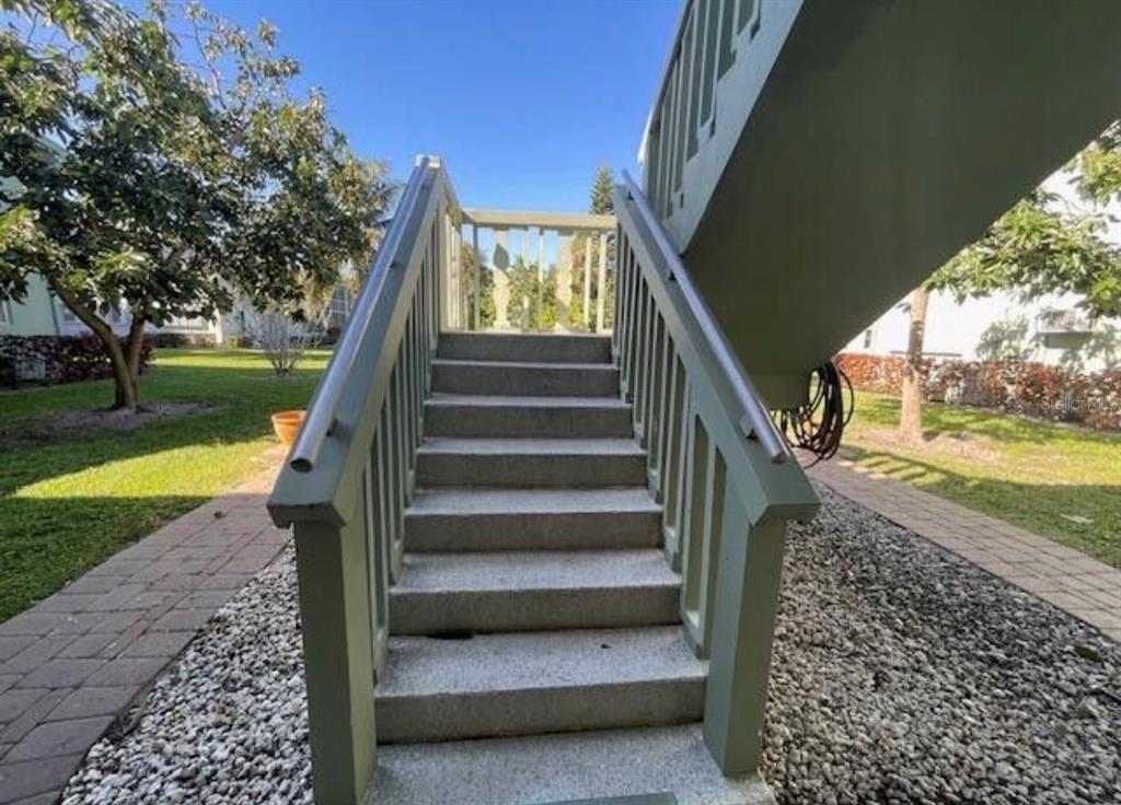 An outdoor concrete staircase with green railings leads up to an elevated wooden deck — 66 EASTHAMPTON UNIT C, WEST PALM BEACH, FL