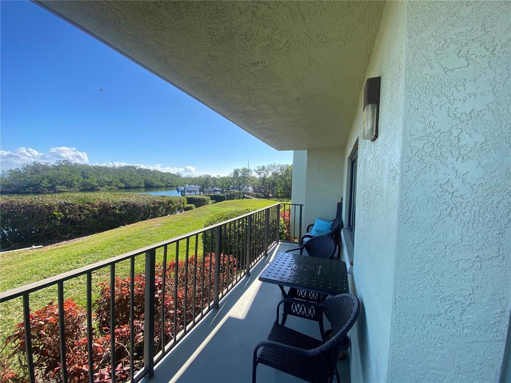 A balcony with a black metal railing overlooks a grassy lawn and the ocean — 1515 PINELLAS BAYWAY S UNIT 1, ST PETERSBURG, FL