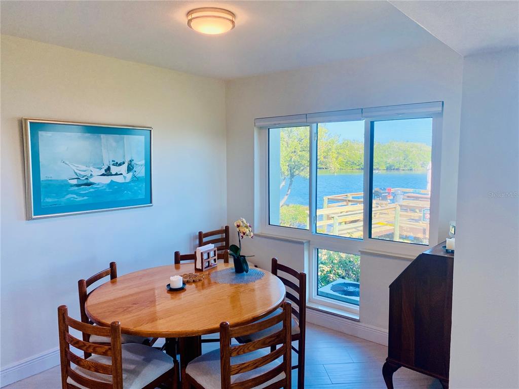 A hallway with light-colored walls and flooring leads toward a room with a recliner chair — 1515 PINELLAS BAYWAY S UNIT 1, ST PETERSBURG, FL