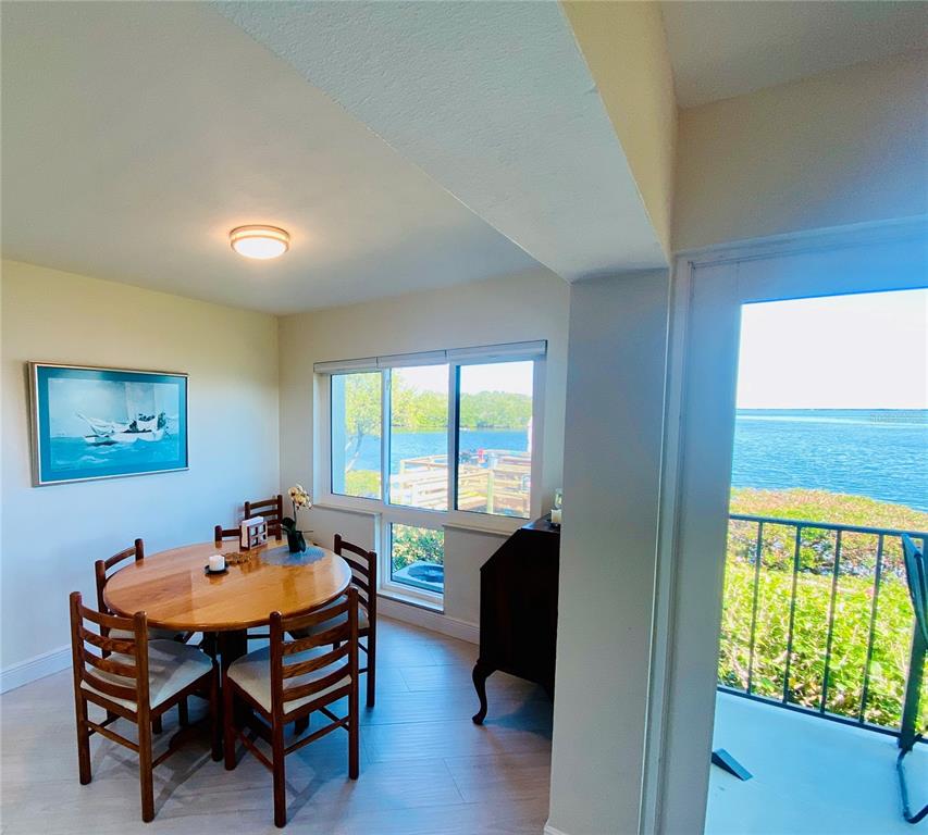 A dining area with a wooden table, chairs, and a window overlooking a waterfront dock — 1515 PINELLAS BAYWAY S UNIT 1, ST PETERSBURG, FL