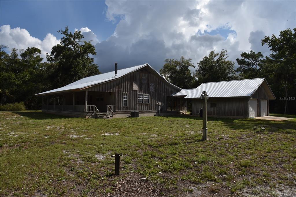 A rustic wooden house with a metal roof and a detached garage in a yard — 5351 SW COUNTY ROAD 347, CEDAR KEY, FL